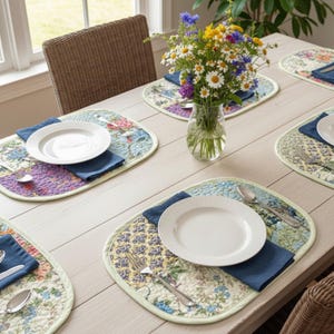 A set of six rectangular placemats with a vibrant, multi-colored floral patchwork design arranged on a wooden dining table.