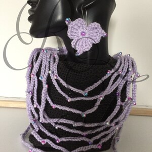 Può includere: Una collana di uncinetto viola con perline iridescenti e orecchini a fiore di uncinetto abbinati. La collana è a strati e ha un aspetto delicato e femminile.