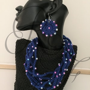 Può includere: Una collana di uncinetto blu con perline iridescenti e orecchini abbinati in uncinetto blu con perline iridescenti.
