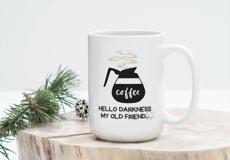 May include: White ceramic coffee mug with a black and white illustration of a coffee pot with steam coming out of it. The text "coffee" is written on the pot. The text "Hello darkness my old friend..." is written below the pot.