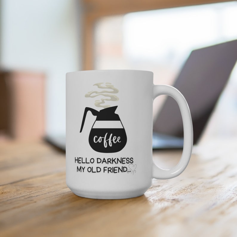 May include: White ceramic coffee mug with a black illustration of a coffee pot with steam rising from the spout. The text "coffee" is written on the pot. The text "Hello darkness my old friend..." is written below the pot.