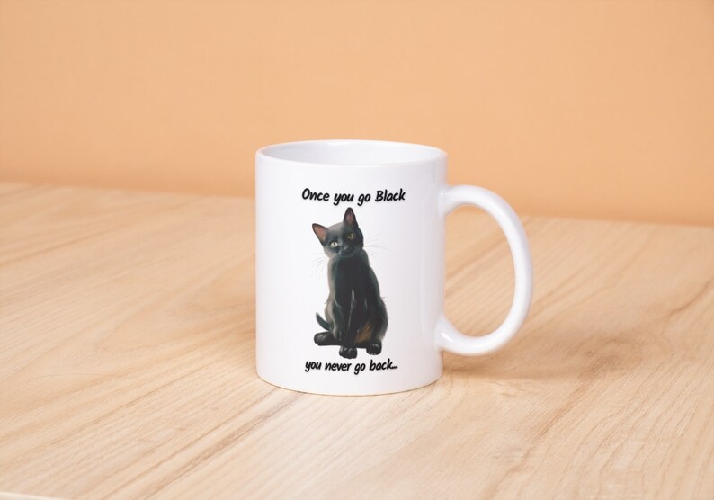 May include: White ceramic mug featuring a black cat illustration with the text "Once you go Black you never go back." The cat is depicted with yellow eyes and a sleek black coat. The mug has a curved handle.