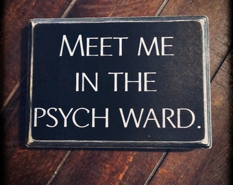 May include: Black wooden sign with white text that reads "Meet me in the psych ward."