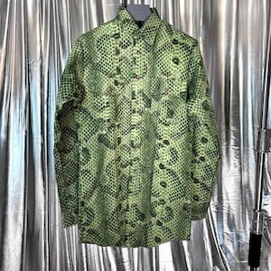 May include: A long-sleeve button-down shirt featuring a vibrant green and black snakeskin pattern. The shirt includes a standard collar, a full-length front button placket, and two chest pockets with buttoned flaps on the front panels.