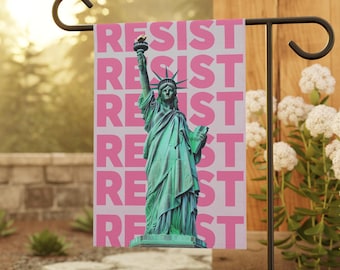Könnte beinhalten: Eine rosafarbene Gartenflagge mit einer grünen Statue der Freiheitsstatue und dem Wort "RESIST" in rosa Buchstaben wiederholt.