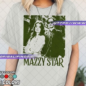 Puede incluir: Camiseta blanca con un gr&aacute;fico verde de dos personas y el nombre de la banda "MAZZY STAR". La camiseta tambi&eacute;n muestra el texto "COLORES DISPONIBLES" y "COLORES BLANCOS".