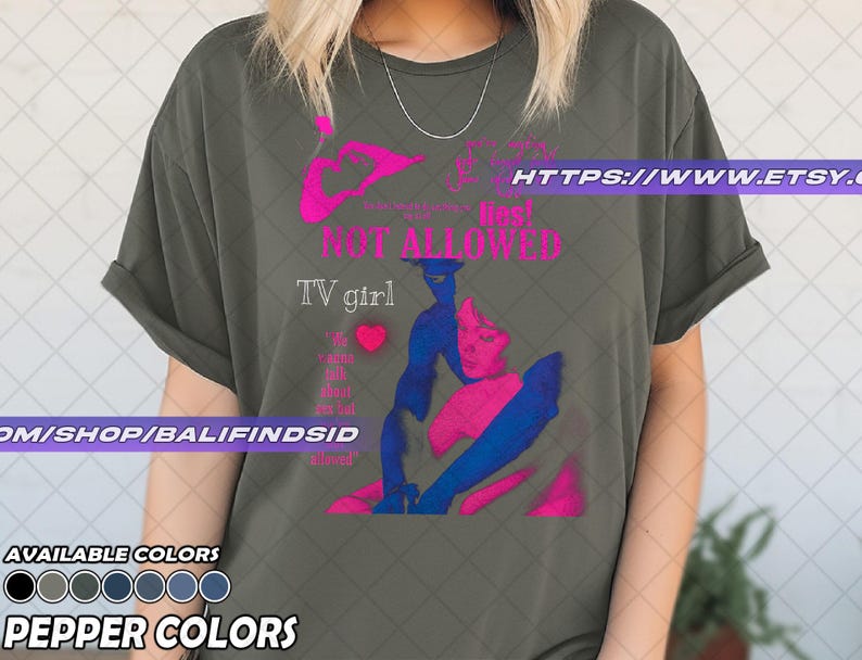 May include: Olive green t-shirt with a graphic design in pink and blue. The design includes the words "NOT ALLOWED" and "TV girl". The shirt also has a heart graphic and the text "I'm alone talk about sex but allowed".