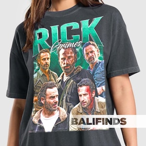 May include: Dark gray t-shirt featuring a graphic of Rick Grimes from The Walking Dead. The design includes the text "Rick Grimes" in green and multiple images of the character. The shirt has a vintage, distressed look.