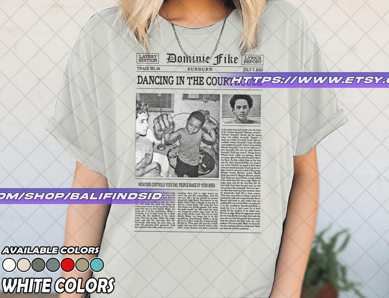 May include: White t-shirt featuring a newspaper-style graphic with the headline "Dancing in the Court" and the name "Dominie Fike." The graphic includes black and white images and text. Available in various colors.