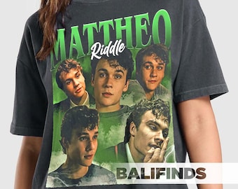 May include: Dark gray t-shirt featuring a collage of images and the name "MATTHEO Riddle" in green and white. The shirt has a vintage, distressed look, with the word "BALIFINDS" printed at the bottom.