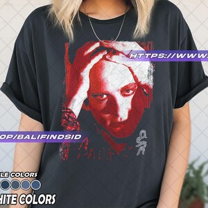 Pu&ograve; includere: T-shirt nero grafite con grafica rossa e bianca di un volto umano. La maglietta include il testo "AVAILABLE COLORS" e "GRAPHITE COLORS" con una tavolozza di colori. L'URL del negozio Etsy &egrave; visibile.