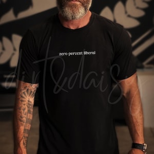May include: Black crew neck t-shirt with the text "zero percent liberal" in white. The shirt is made of a soft material. The person wearing the shirt has a beard and a tattoo on their arm.