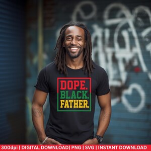 May include: Black t-shirt with the text "DOPE. BLACK. FATHER." in red, green, and yellow. The text is enclosed in a red and green rectangular border. The person wearing the shirt is smiling.