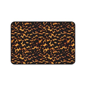 Op de afbeelding: Rechthoekige muismat met een schildpadpatroon. Het ontwerp heeft een herhalend patroon van onregelmatige vormen in donkerbruin en goudgeel, waardoor een gevlekt effect ontstaat. De muismat heeft afgeronde hoeken en een zwarte rand.