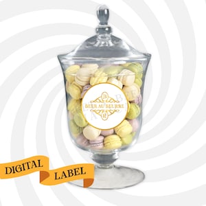May include: A glass jar filled with colorful macarons. A white round label with gold lettering reads "BEER AU BEURRE" with a decorative design.