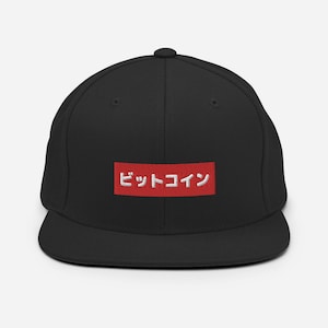 Puede incluir: Gorra de béisbol negra ajustada con una caja roja y texto blanco que dice "ビットコイン" (Bitcoin en japonés).