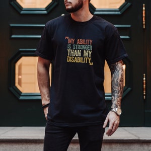 May include: A black t-shirt with a vintage-style graphic that reads "My ability is stronger than my disability."