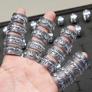 May include: A set of silver rings featuring an elephant design. The rings are stacked on a hand, showcasing the intricate detail of the elephant carvings.