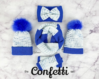 May include: A blue and white knit hat, scarf, and headband set with a pom pom on each hat. The set is called "the Confetti set".