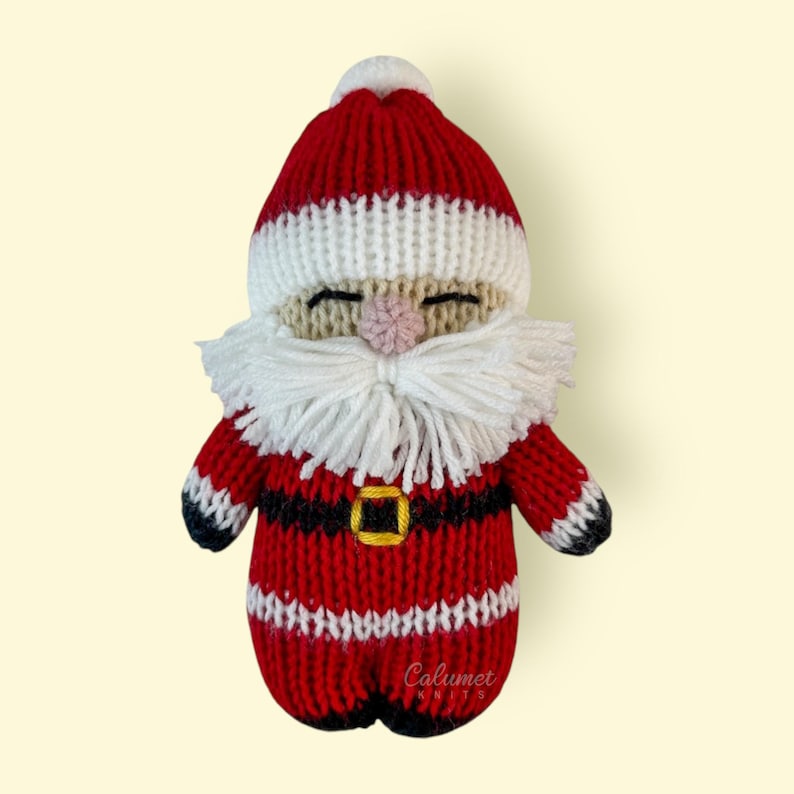 K&ouml;nnte beinhalten: Eine gestrickte Weihnachtsmann-Puppe mit wei&szlig;em Bart und roter und wei&szlig;er M&uuml;tze. Die Puppe tr&auml;gt einen roten Anzug mit schwarzem G&uuml;rtel und wei&szlig;en Verzierungen. Die Puppe l&auml;chelt und hat eine rote Nase.