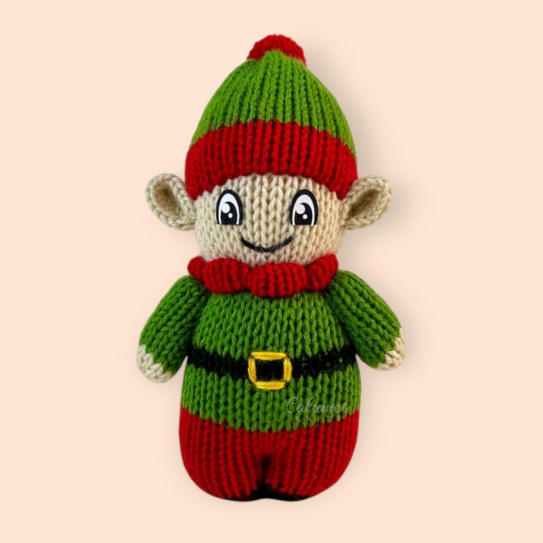 K&ouml;nnte beinhalten: Eine gestrickte Elfenpuppe mit gr&uuml;nem Hut, rot-gr&uuml;nem gestreiftem K&ouml;rper und einem schwarzen G&uuml;rtel. Der Elf hat ein l&auml;chelndes Gesicht mit schwarzen Augen und einem roten Mund.