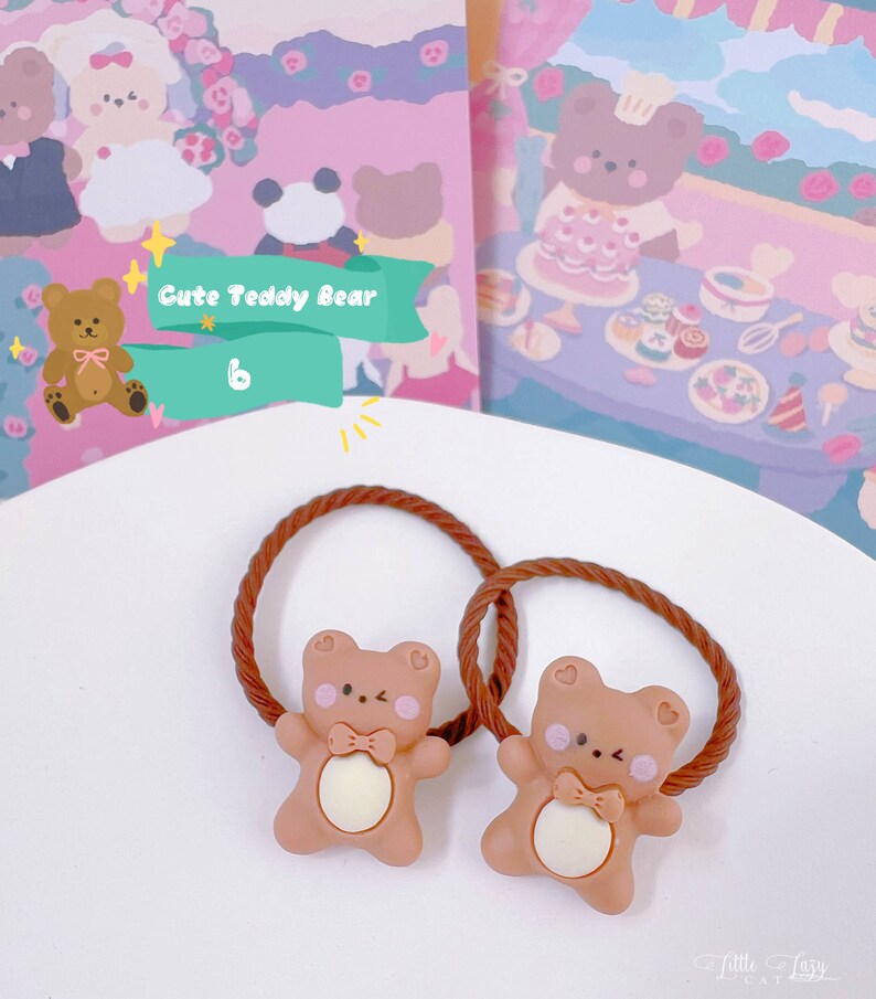 May include: Two brown hair ties with a cute teddy bear design. Each bear has a bow tie and a heart on its cheek. The background features illustrations of teddy bears and the text "Cute Teddy Bear".