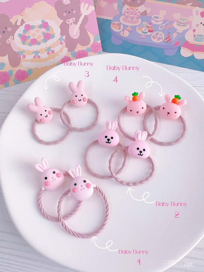May include: A collection of pink hair ties, each adorned with a cute, cartoon-style bunny face. Some bunnies have carrot accents. The hair ties are arranged on a white plate, with the text "Baby Bunny" and numbers labeling each.