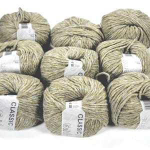 以下が含まれることがあります： ニュートラルで斑点のある色のClassic Soft Tweed糸の10個のかせのコレクション。各糸玉は、他の色の斑点のある明るいオリーブグリーンです。糸にはブランド名と製品の詳細が記載されています。