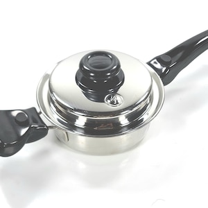 Puede incluir: Cacerola de acero inoxidable con asa y tapa negras. La tapa tiene un pomo negro y un pequeño logotipo. El asa tiene un lazo para colgar. La cacerola tiene un asa lateral negra.