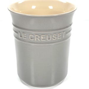Op de afbeelding: Een grijze Le Creuset keukengerei houder. De cilindrische houder heeft een lichtbeige binnenkant en de merknaam is in reliëf op de zijkant. De keukengereihouder is gemaakt van keramiek en heeft een gladde afwerking. De houder is ontworpen om keukengerei in te bewaren.