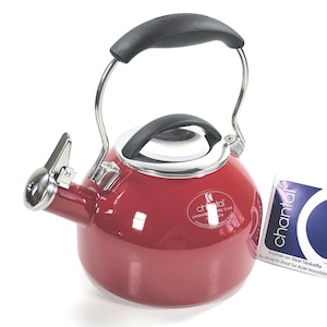 Op de afbeelding: Een rode geëmailleerde stalen theeketel met een zwarte handgreep en een zilveren tuit. De ketel heeft een zilveren rand en een zwarte handgreep aan de bovenkant. Een label met de merknaam "Chantal" is bevestigd.