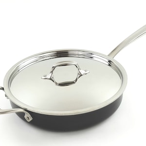 Può includere: Una pentola in acciaio inox All-Clad nera e argentata con coperchio. La pentola ha un manico lungo e un piccolo manico sul coperchio.