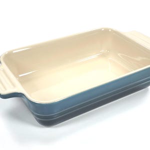 Pode incluir: Assadeira retangular de cerâmica com interior creme claro e exterior azul gradiente. A assadeira tem duas alças e é adequada para assar caçarolas, sobremesas ou outros pratos. A assadeira tem aproximadamente 30 cm de comprimento.