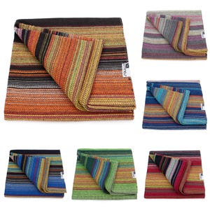 May include: A collection of six folded woven blankets featuring horizontal stripes in various color palettes including orange, black, blue, green, and red. Each blanket has a white rectangular tag with the text SOULLY printed in black.