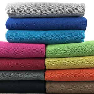 Pode incluir: Uma pilha de dez toalhas de tecido em várias cores, incluindo cinza, azul, turquesa, rosa, verde, amarelo, laranja, preto e marrom. As toalhas estão dobradas e empilhadas umas sobre as outras.