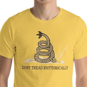 May include: A yellow short-sleeved t-shirt with a graphic of a coiled snake with the text "Don't Tread Rhythmically".