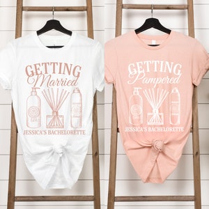 Puede incluir: Dos camisetas blancas con un dise&ntilde;o en color oro rosa. La camiseta de la izquierda dice "Getting Married" y la camiseta de la derecha dice "Getting Pampered". Ambas camisetas tienen un dise&ntilde;o de tres botellas y un difusor con palitos. El texto en la parte inferior de ambas camisetas dice "Jessica's Bachelorette".