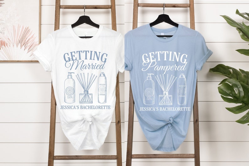 Puede incluir: Dos camisetas blancas con texto y gr&aacute;ficos azules. La camiseta de la izquierda dice "Getting Married" y la camiseta de la derecha dice "Getting Pampered". Ambas camisetas tienen un gr&aacute;fico de tres botellas de productos de spa y dicen "Jessica's Bachelorette" en la parte inferior.