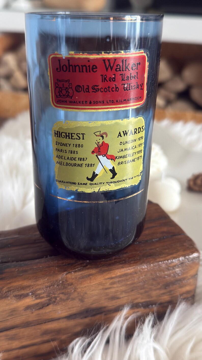 May include: A blue glass with Johnnie Walker Red Label Old Scotch Whisky labels. The labels list awards from various cities and the text "Guaranteed Same Quality Throughout The World."