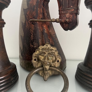 Op de afbeelding: Een donkerbruin houten paardenkopsculptuur met gedetailleerde koperen accenten, een hoofdstel en een opvallende koperen leeuwenkop-deurklopper aan de voorzijde. Het beeld wordt geflankeerd door twee donkerbruine houten schaakstuk-voetstukken.