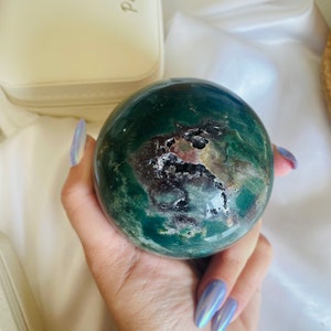 以下が含まれることがあります： 緑、茶色、白の渦巻き模様の球体。球体は磨かれた石でできており、滑らかで光沢のある仕上がりです。