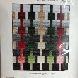 Puede incluir: Patrón de acolchado "Block It Out" con un diseño geométrico de cuadrados de tela rojos, verdes, beige y grises. La colcha mide 46 pulgadas por 54 pulgadas. El patrón es de Gourmet Quilter, una empresa especializada en patrones de acolchado.