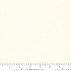 May include: A pale cream fabric featuring a repeating pattern of white cursive handwriting script. A ruler is visible at the bottom edge, showing a scale of 7 inches, with the text moda and www.modafabrics.com printed along the bottom.