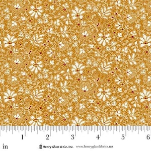May include: Mustard-colored fabric with a repeating floral pattern. The design features white flowers with red accents and small dots. The fabric is measured in inches along the bottom edge.
