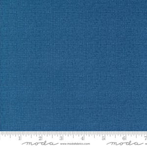 May include: A close-up of a solid blue fabric with a subtle textured pattern. The fabric is measured with a ruler in inches.
