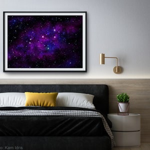 May include: A framed print of a galaxy with purple and blue nebulae and white stars against a black background. The print is hanging on a white wall above a black headboard with a yellow pillow and white bedding.