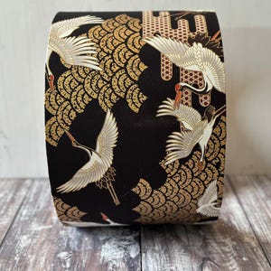 May include: Drum lampshade with a repeating pattern of white cranes, gold and red accents. The cranes are in flight against a backdrop of gold fan-shaped designs.