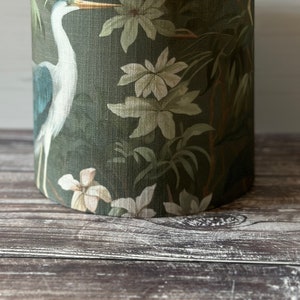 May include: A green lampshade with a white heron and floral pattern.