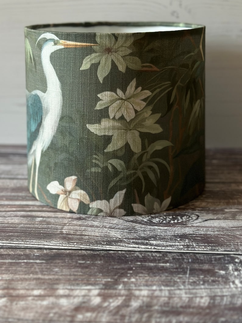 May include: A green lampshade with a white heron and floral pattern.