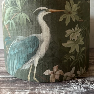 May include: A green lampshade with a white heron and green foliage pattern.